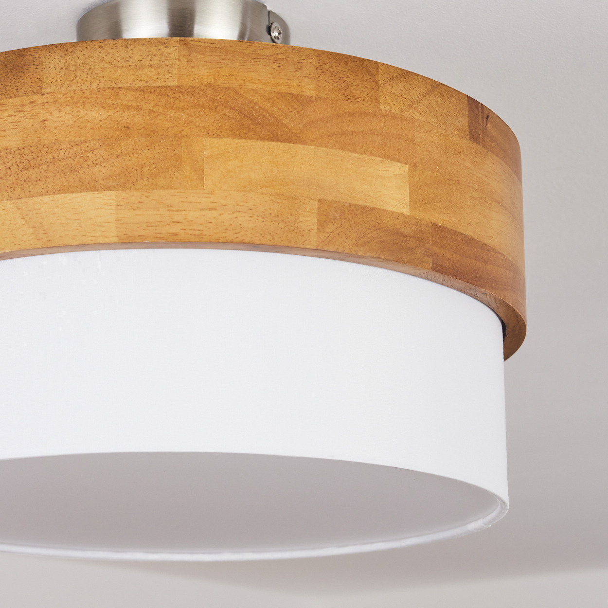 Nahaufnahme einer Deckenlampe mit Holzaufsatz und weißem Lampenschirm.