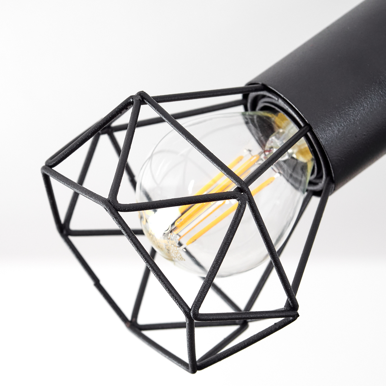 Eine schwarze Metallkäfiglampe mit Diamantform und Glühbirne.