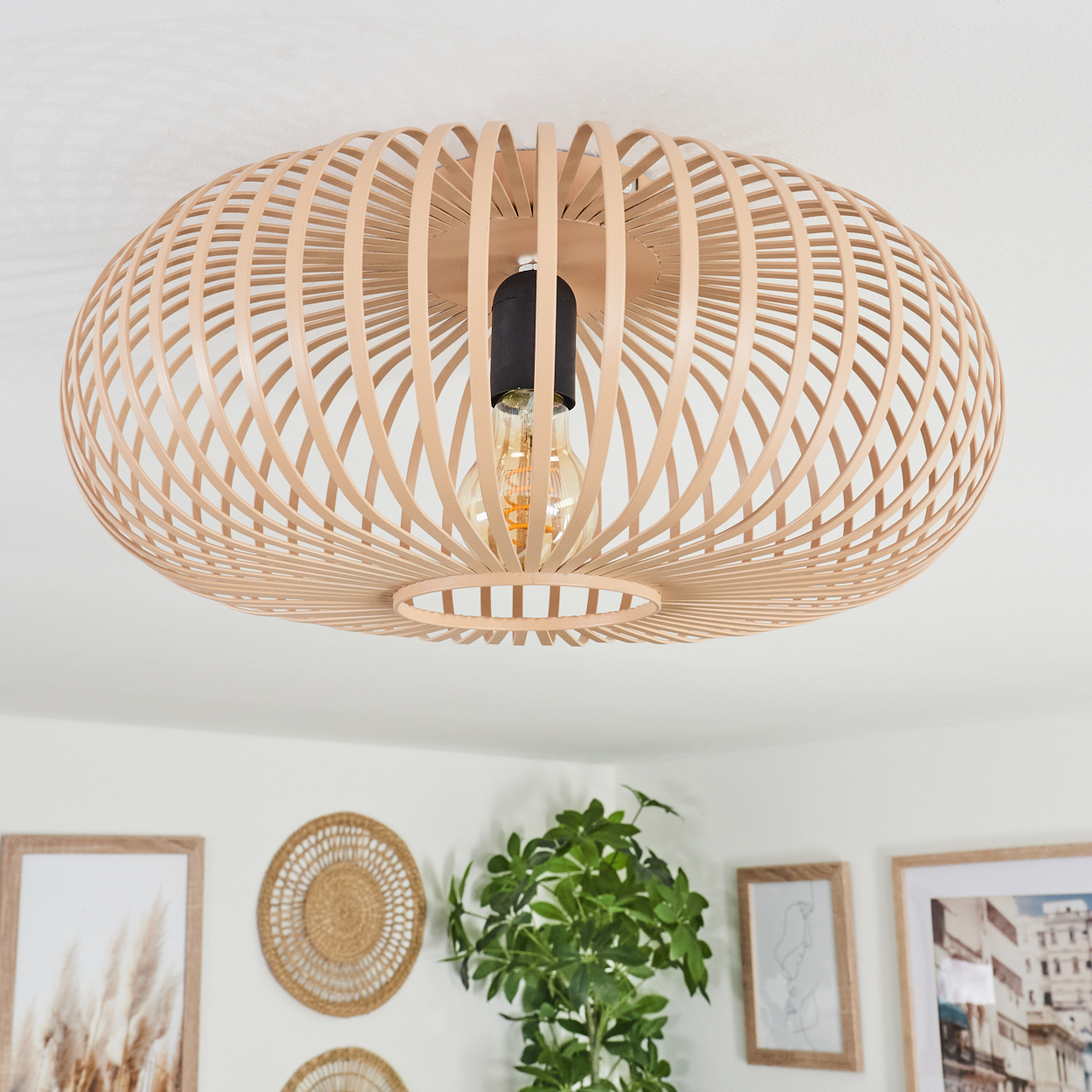 Deckenlampe aus Holzlamellen mit sichtbarer Glühbirne, Hintergrund mit Kunst und Pflanzen.
