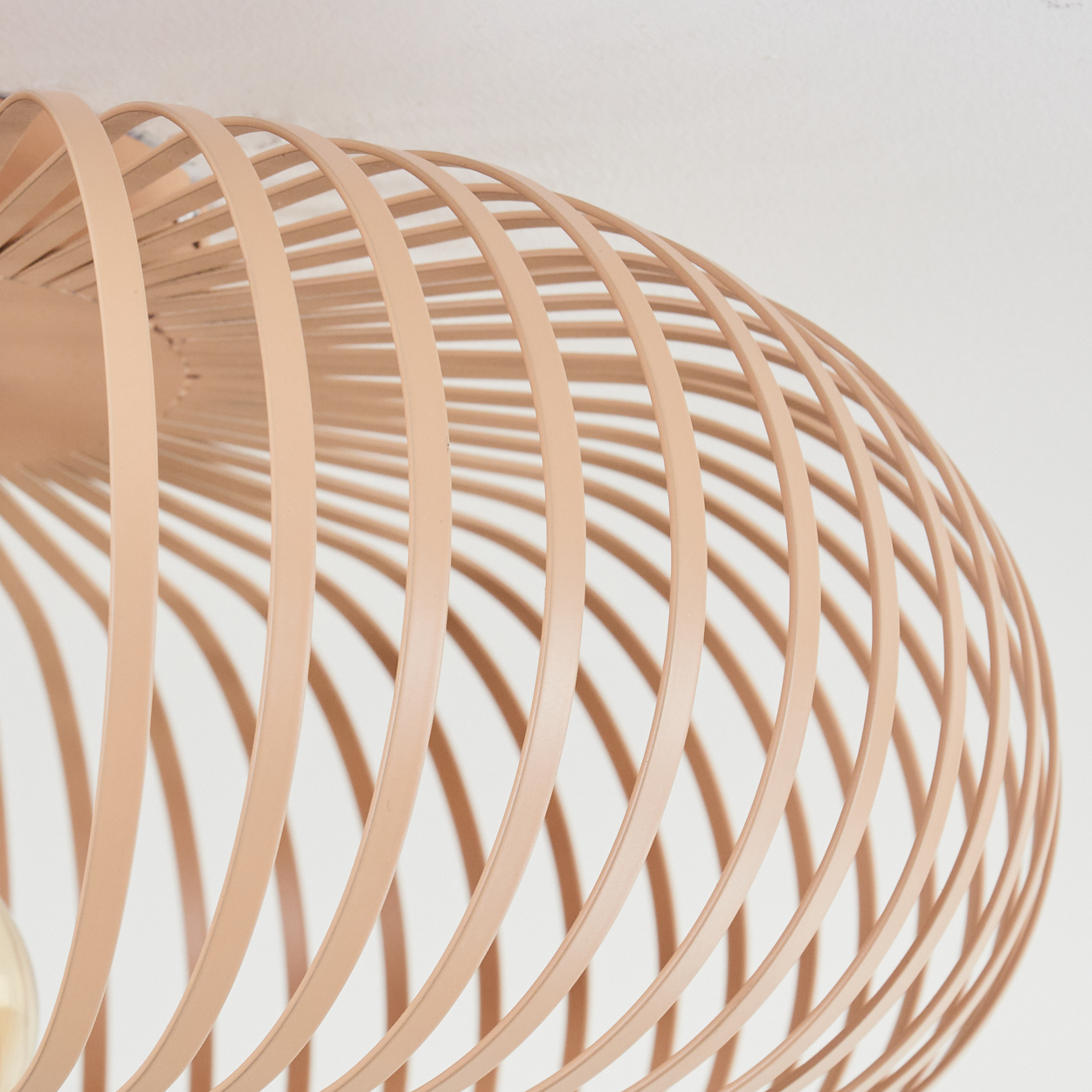 Nahaufnahme einer beigen, kreisförmigen Deckenlampe mit Lamellen.