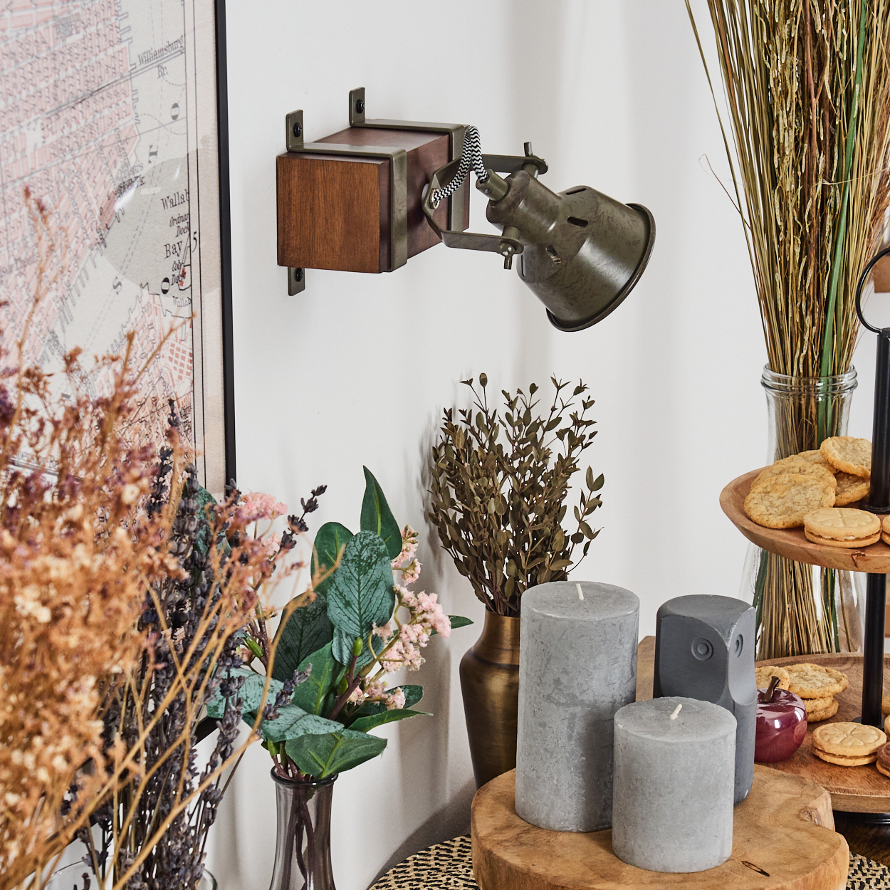 Wandleuchte, Kerzen und Pflanzen, mit Karte und Trockenblumen an der Wand.
