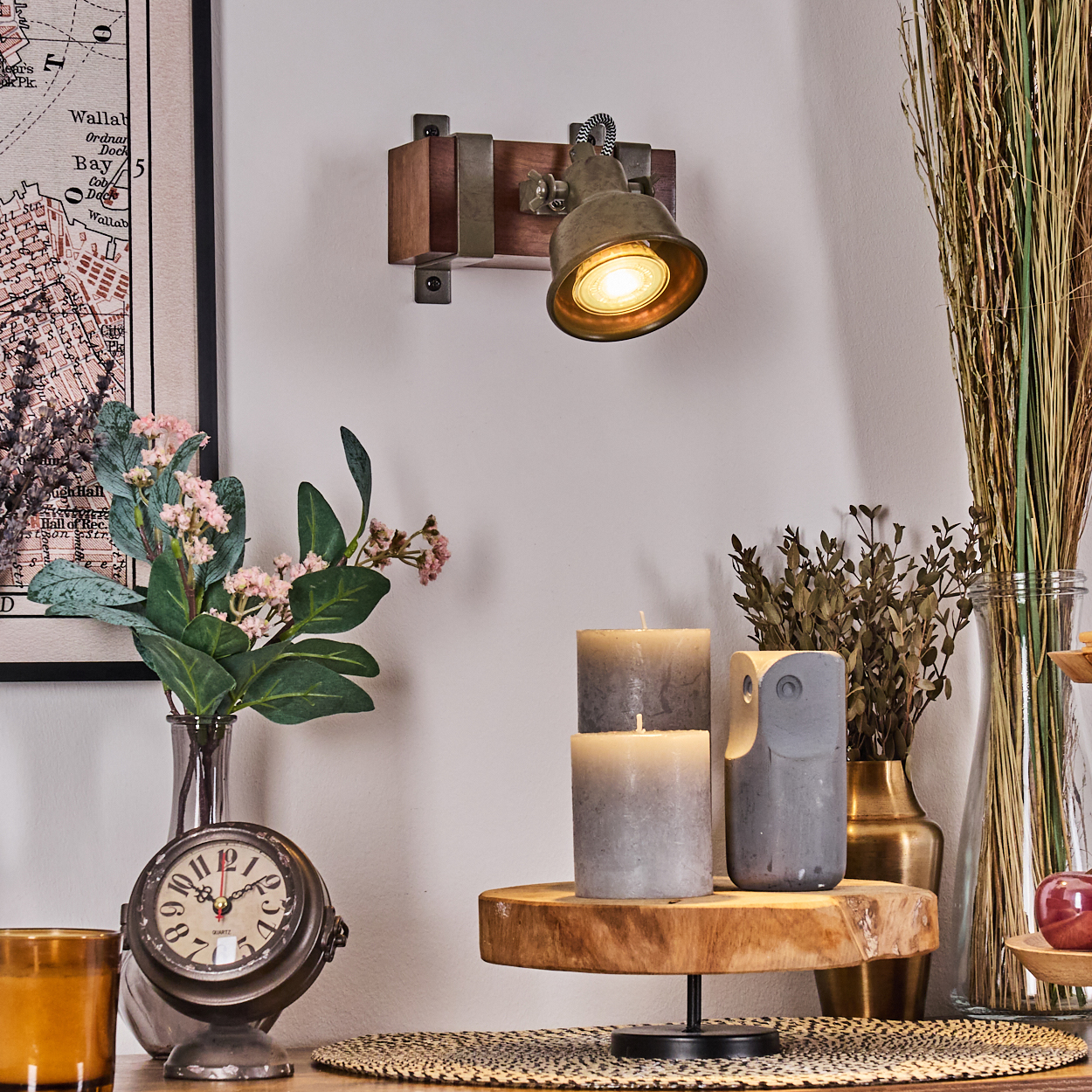 Eine Wandlampe mit Messing-Lampenschirm ist auf einer Holzplatte mit Karte und Dekor montiert.