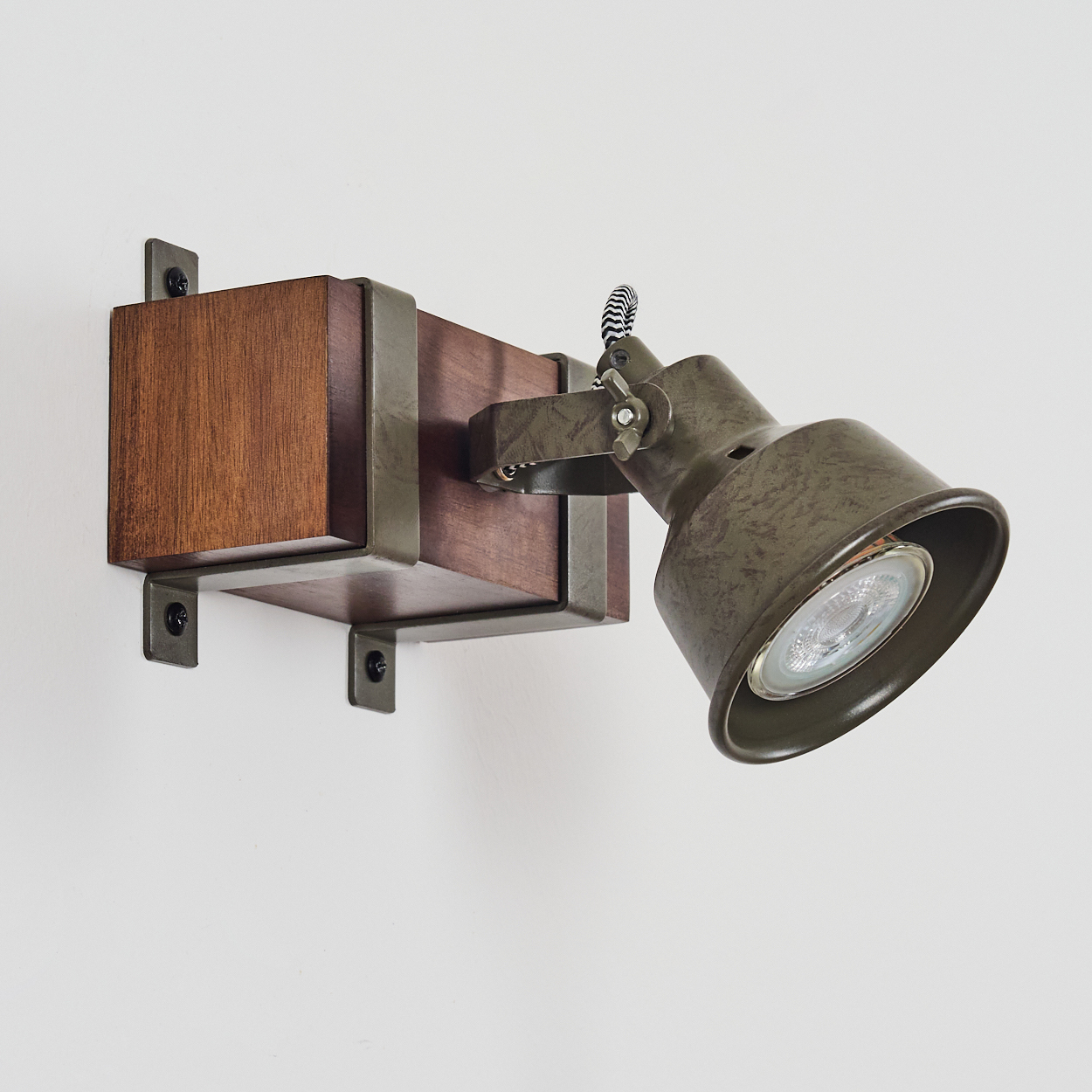 Eine Holzlampe mit grünem Lampenkopf. Die Lampe ist an einer Wand montiert.