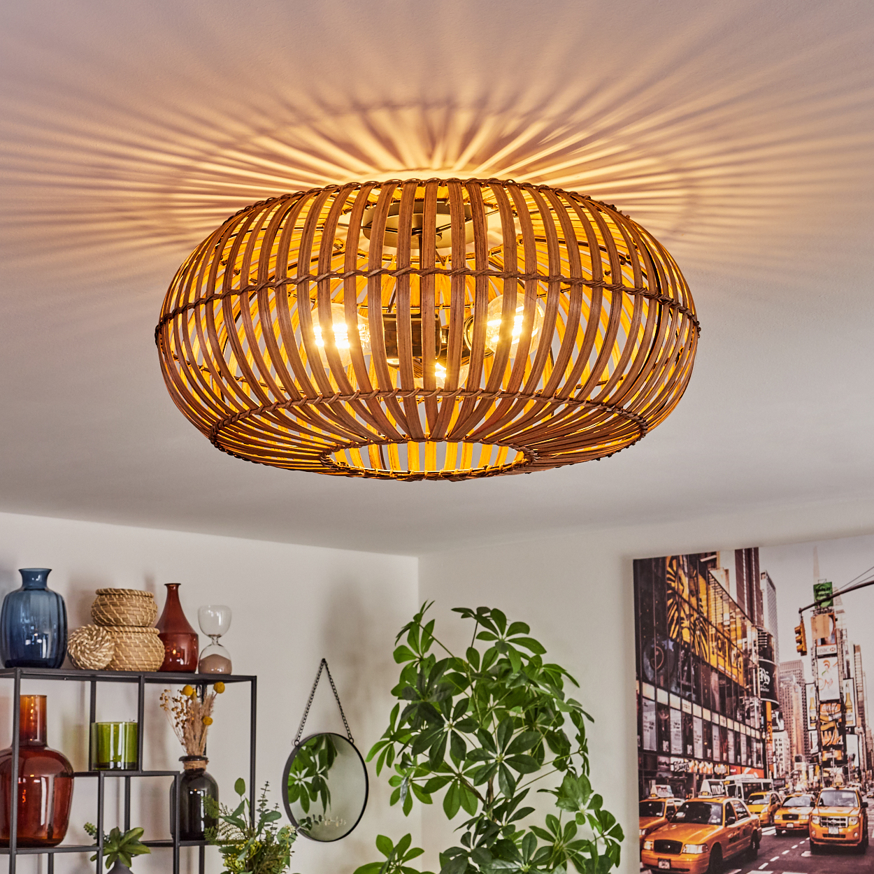 Eine Rattanlampe hängt von der Decke. Sie ist oval und beleuchtet den Raum darunter.