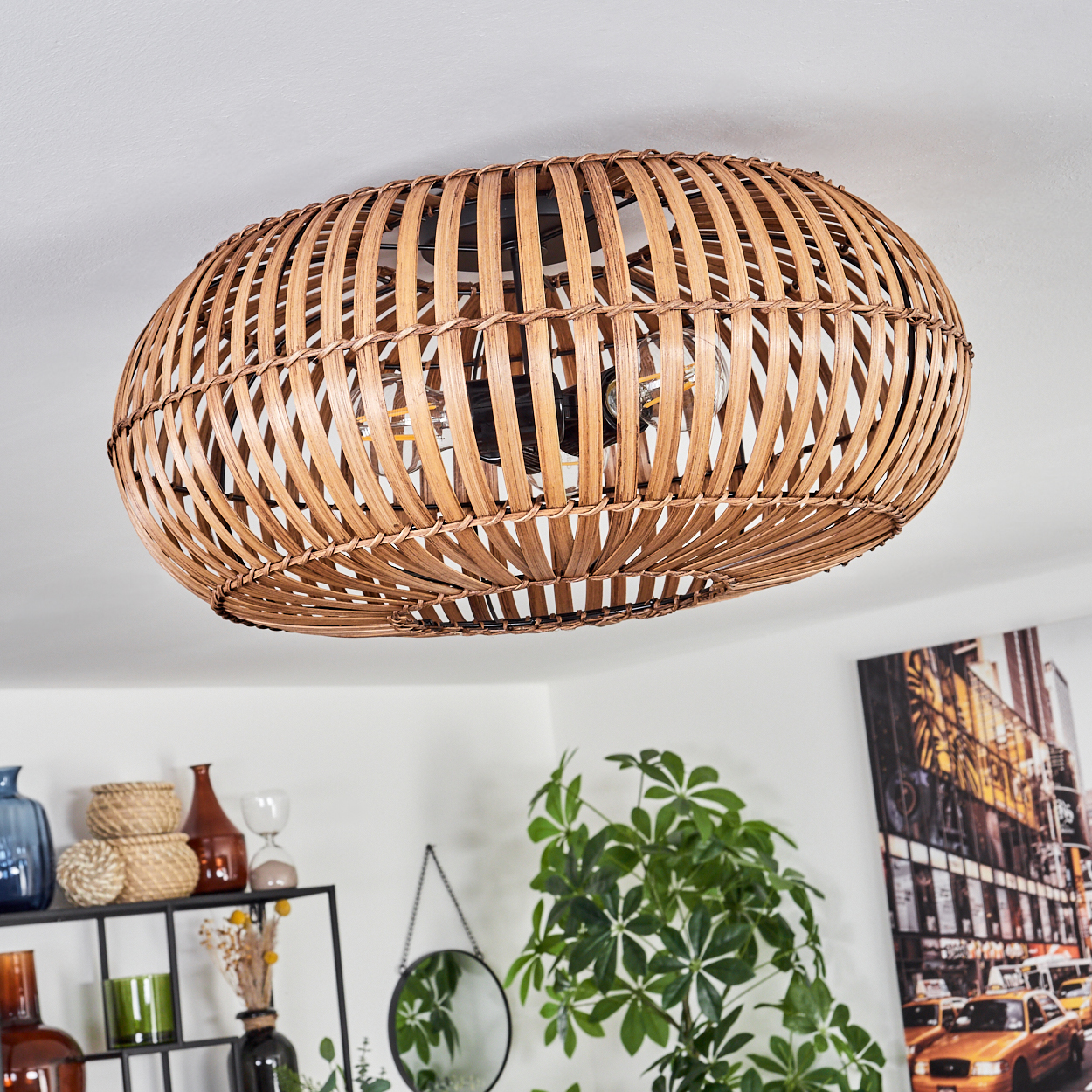 Eine Deckenlampe aus geflochtenem Rattan. Die Lampe hat eine ovale Form und ist vor weißem Hintergrund.