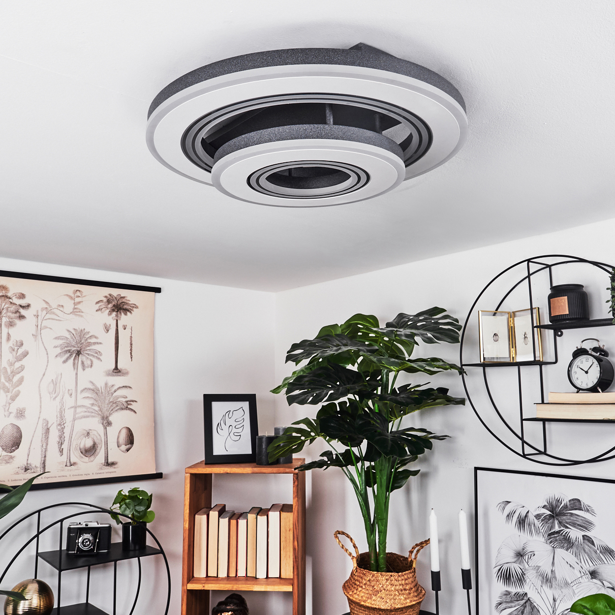 Eine moderne Deckenleuchte mit kreisförmigem Design in Weiß, Grau und Schwarz, über einer Raumszene.