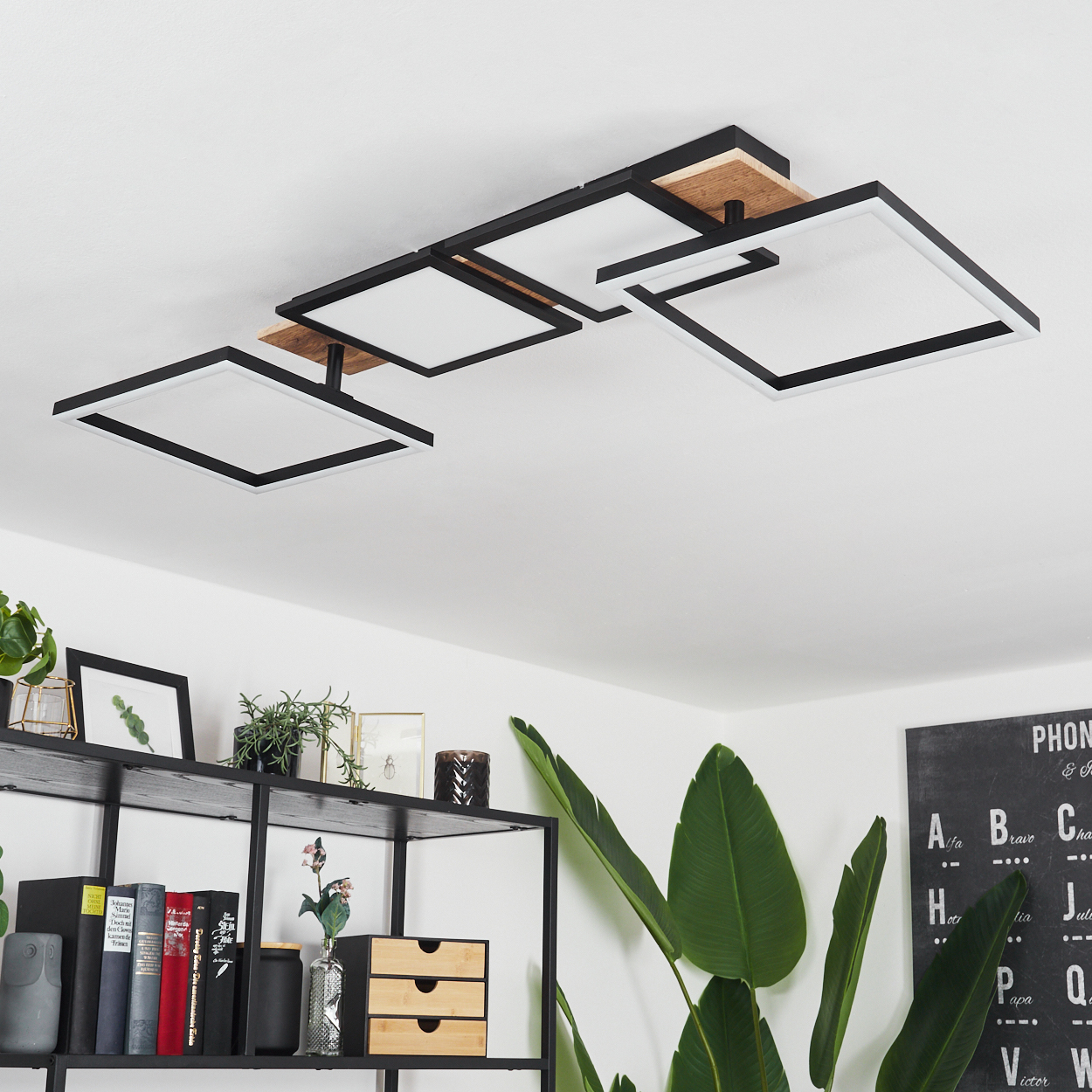 Eine Deckenleuchte mit quadratischen weißen Lichtern und schwarzen Rahmen. Unten sind Regale mit Pflanzen und Büchern sowie eine Tafel.
