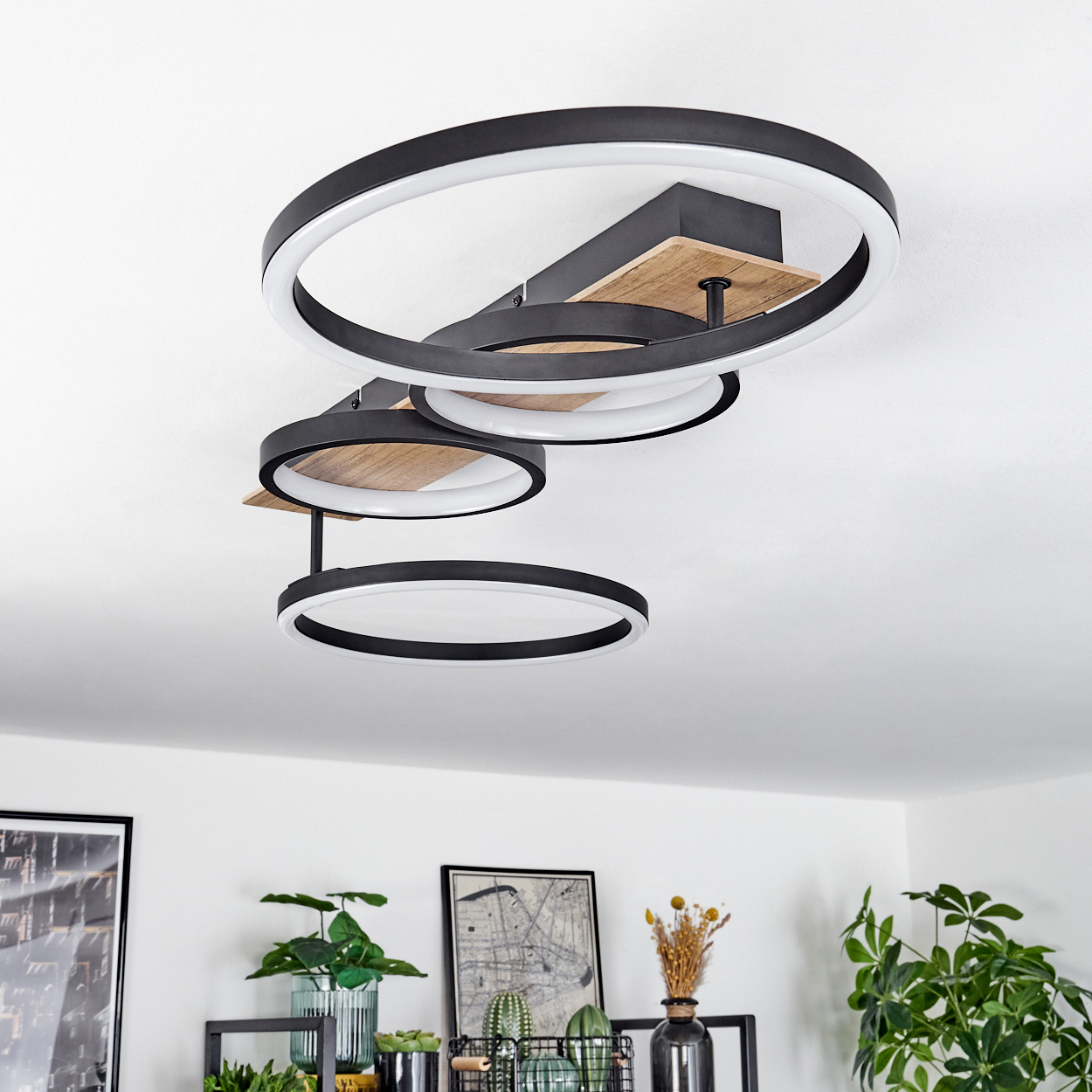 Deckenleuchte mit drei kreisförmigen Ringen in Schwarz und Weiß. Das Licht ist über einem Holzsockel montiert.