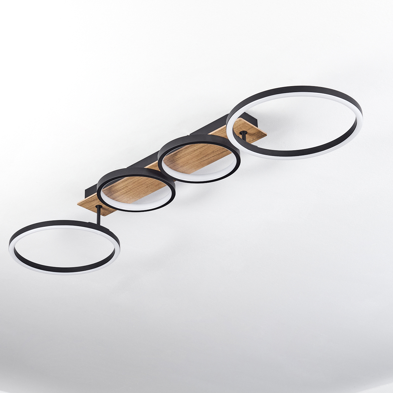 Deckenlampe mit drei schwarz-weißen Ringen, an Holz befestigt, vor weißem Deckenhintergrund.