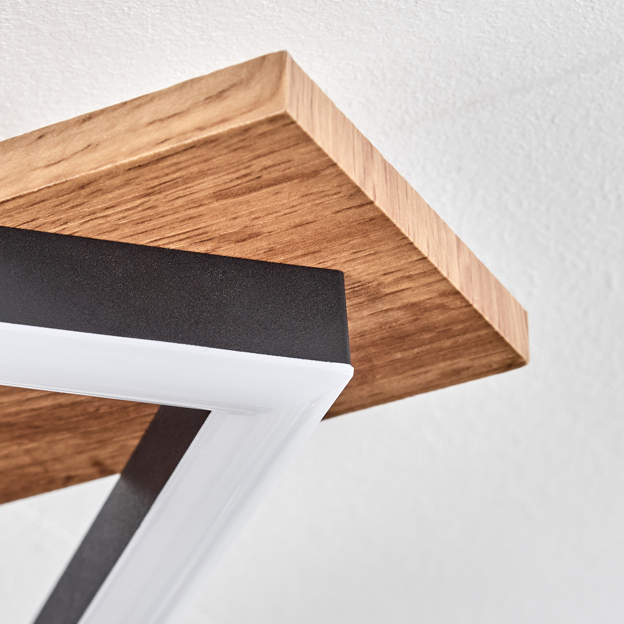 Nahaufnahme einer Deckenlampe mit Holz- und schwarzem Rahmen, die Konstruktionsdetails zeigt.