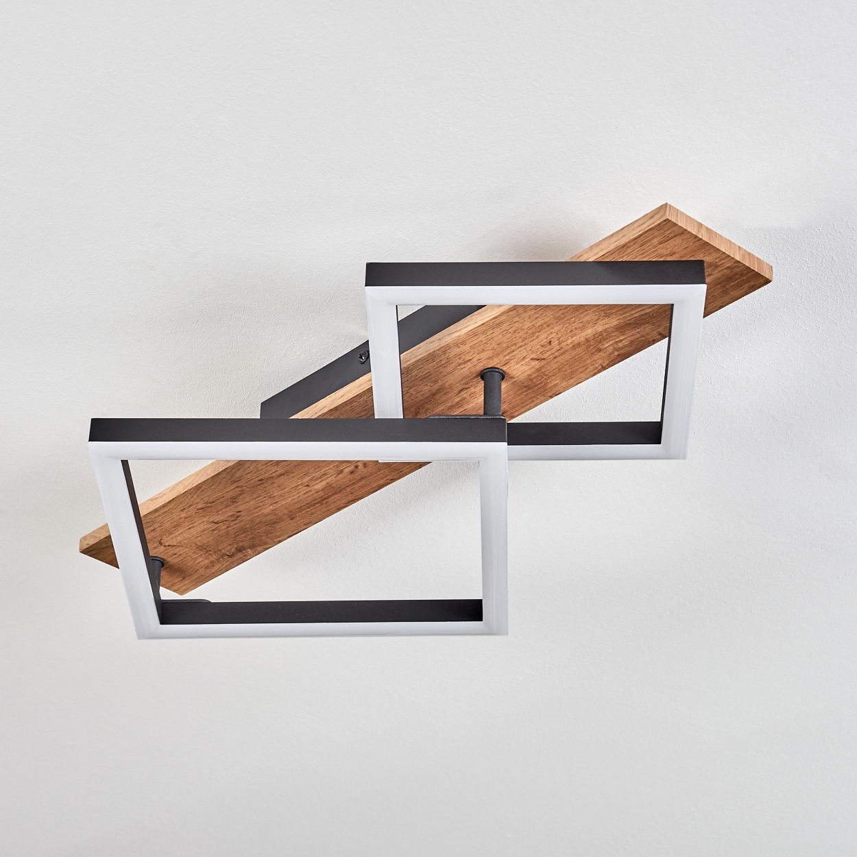 Eine Deckenleuchte mit zwei quadratischen Lichtquellen. Sie hat einen Holzsockel und die Quadrate sind schwarz und weiß.