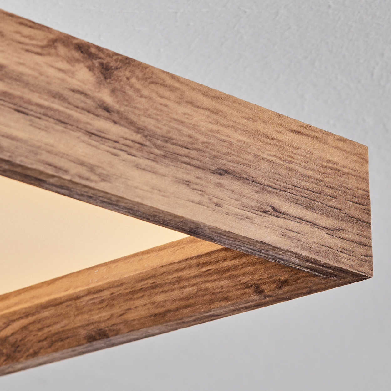 Nahaufnahme einer Deckenleuchte mit Holzrahmen und weißem Lichtpaneel.
