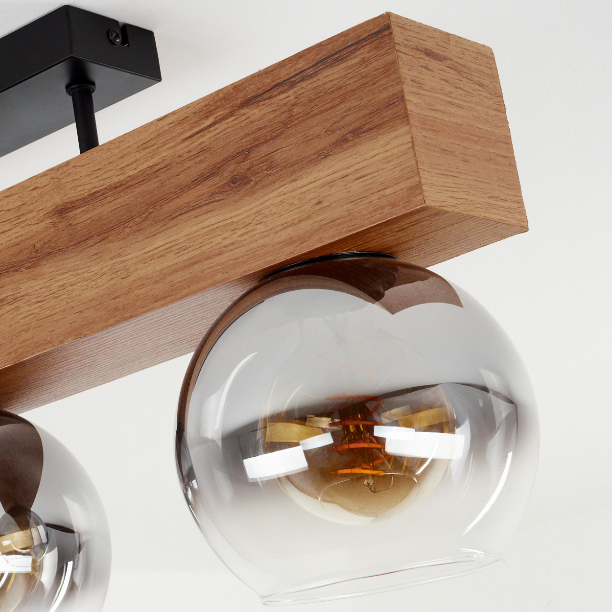 Nahaufnahme eines Holzbalkenlichts mit drei Glaskugellampen, die Details des Designs zeigend.