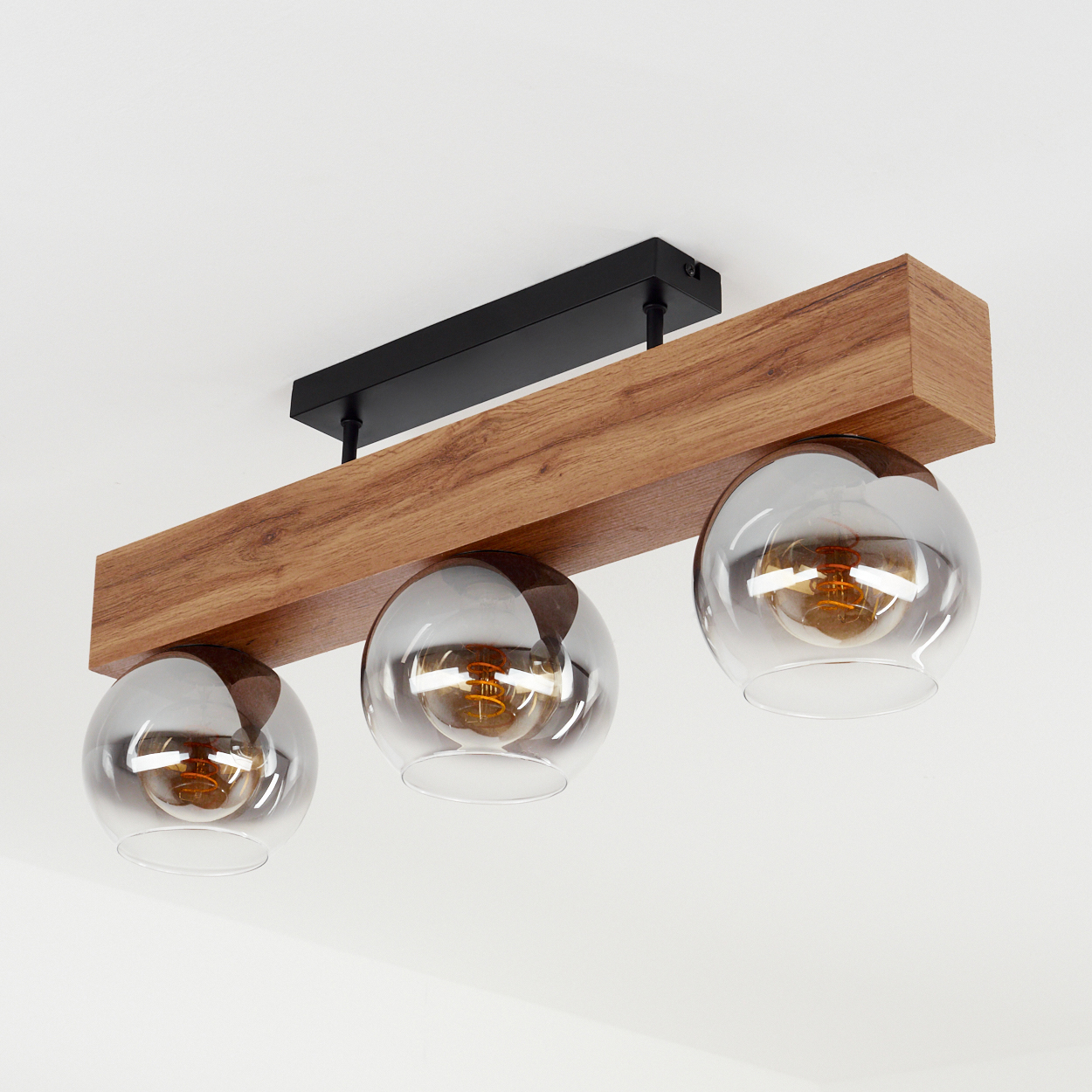 Ein Holzbalkenlicht mit drei Glaskugelleuchten hängt von der Decke, gut beleuchtet, sauberer Hintergrund.