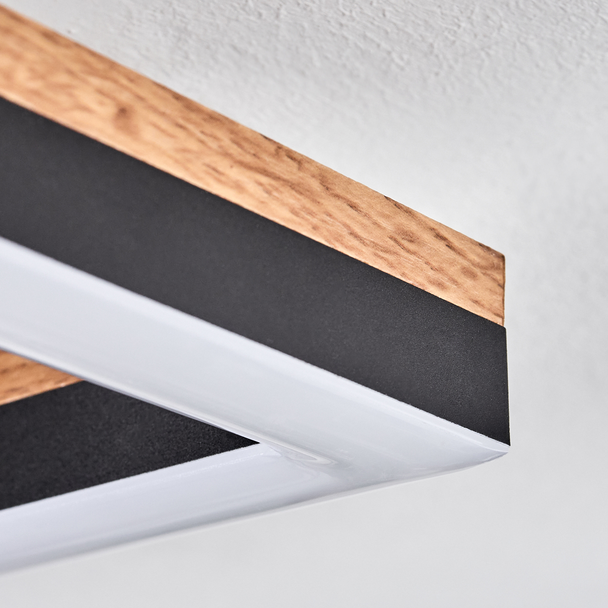 Nahaufnahme des Rahmens einer Deckenleuchte. Sie hat einen Holzrand und ein schwarz-weißes Design.