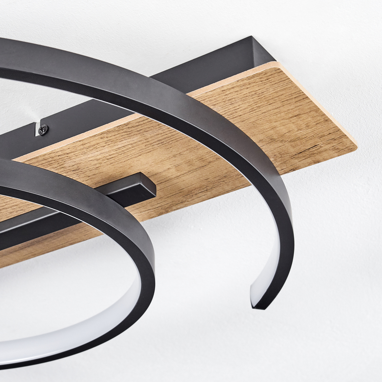 Nahaufnahme einer Deckenlampe mit Holzsockel und schwarzen Metallelementen.