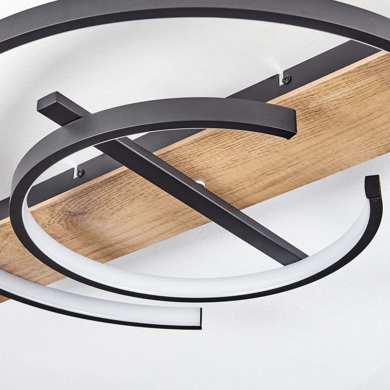 Nahaufnahme einer Deckenlampe mit Holzsockel und schwarzen Metallelementen.