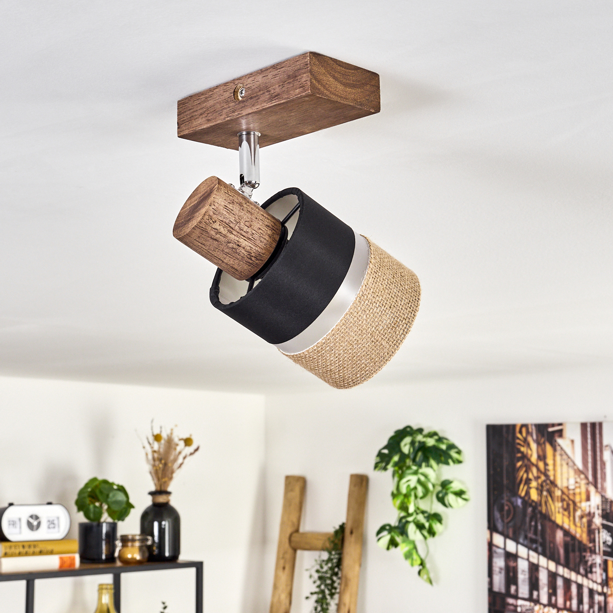 Abgewinkelter Strahler mit schwarzem, Jute-Schirm und Holzsockel. Innenraum mit Pflanzen.