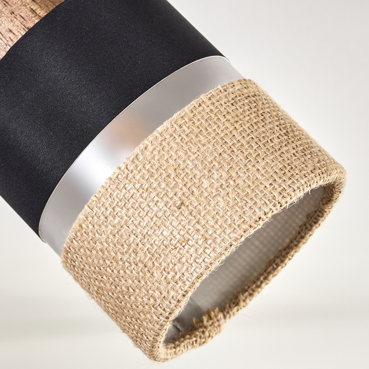 Nahaufnahme eines Scheinwerfer-Schirms mit schwarzem Stoff, silbernem Ring und Jute-Textur.