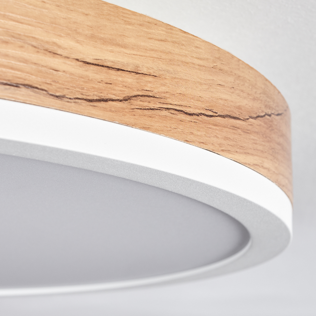 Nahaufnahme einer runden Deckenlampe mit Holzverkleidung und weißem Innenkreis.