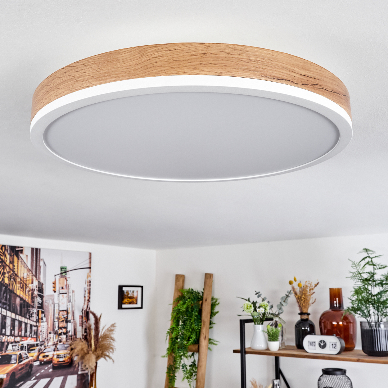 Runde Deckenleuchte mit Holzrahmen. Das Licht ist weiß und der Rahmen braun. Der Hintergrund ist eine weiße Decke.