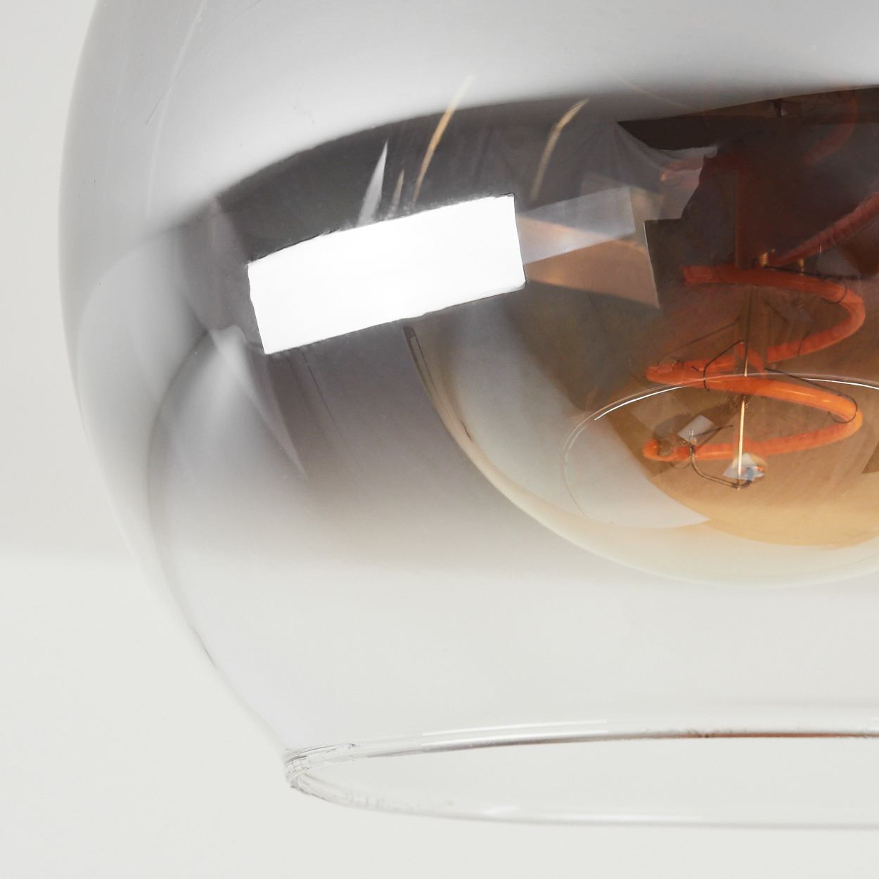 Nahaufnahme einer transparenten Glühbirne mit goldenem Glühfaden. Weißer Hintergrund.