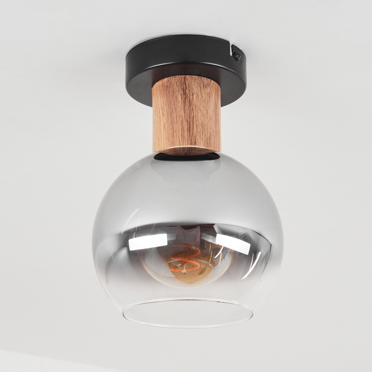 Deckenlampe mit kreisförmigem Design aus Holz und Schwarz. Klarglas-Glühbirne. Weißer Hintergrund.