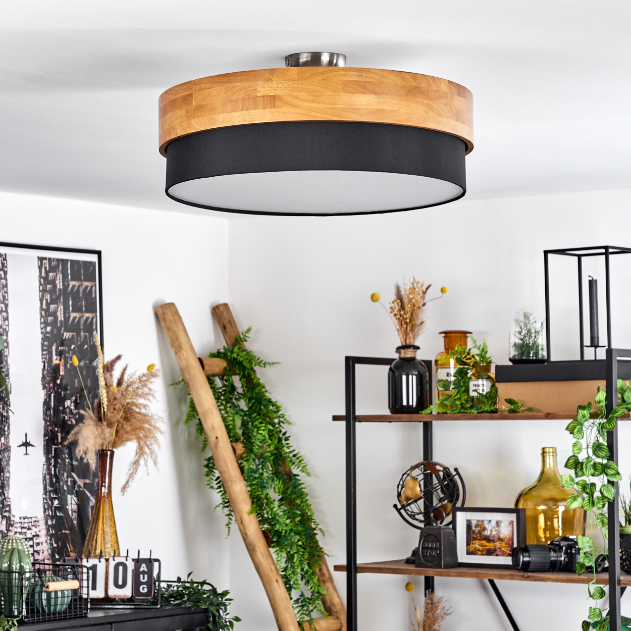Eine dreistufige Leuchte mit Holz und schwarzem Stoff steht in einem Raum.