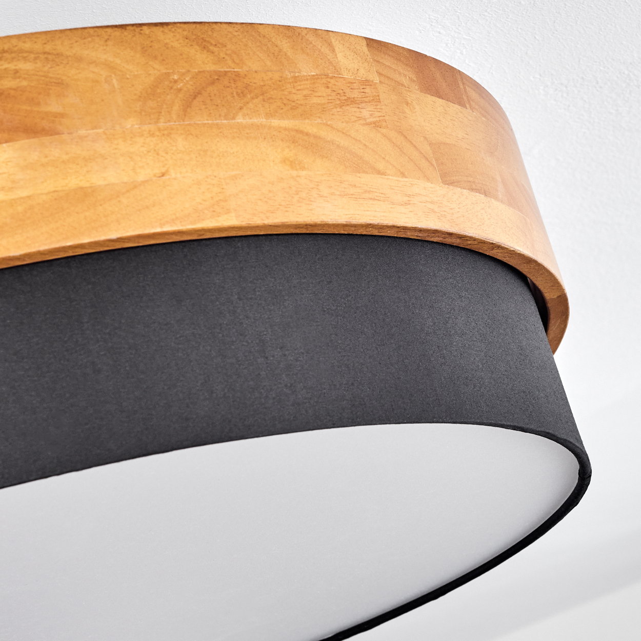 Nahaufnahme einer Deckenlampe mit Holz- und schwarzen Elementen. Weißer Hintergrund.