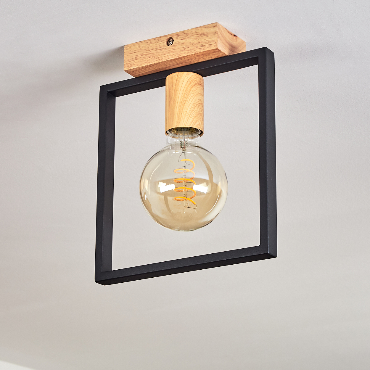 Deckenleuchte mit schwarzem quadratischem Rahmen, Holzakzent und leuchtender Glühbirne. Das Licht ist an.