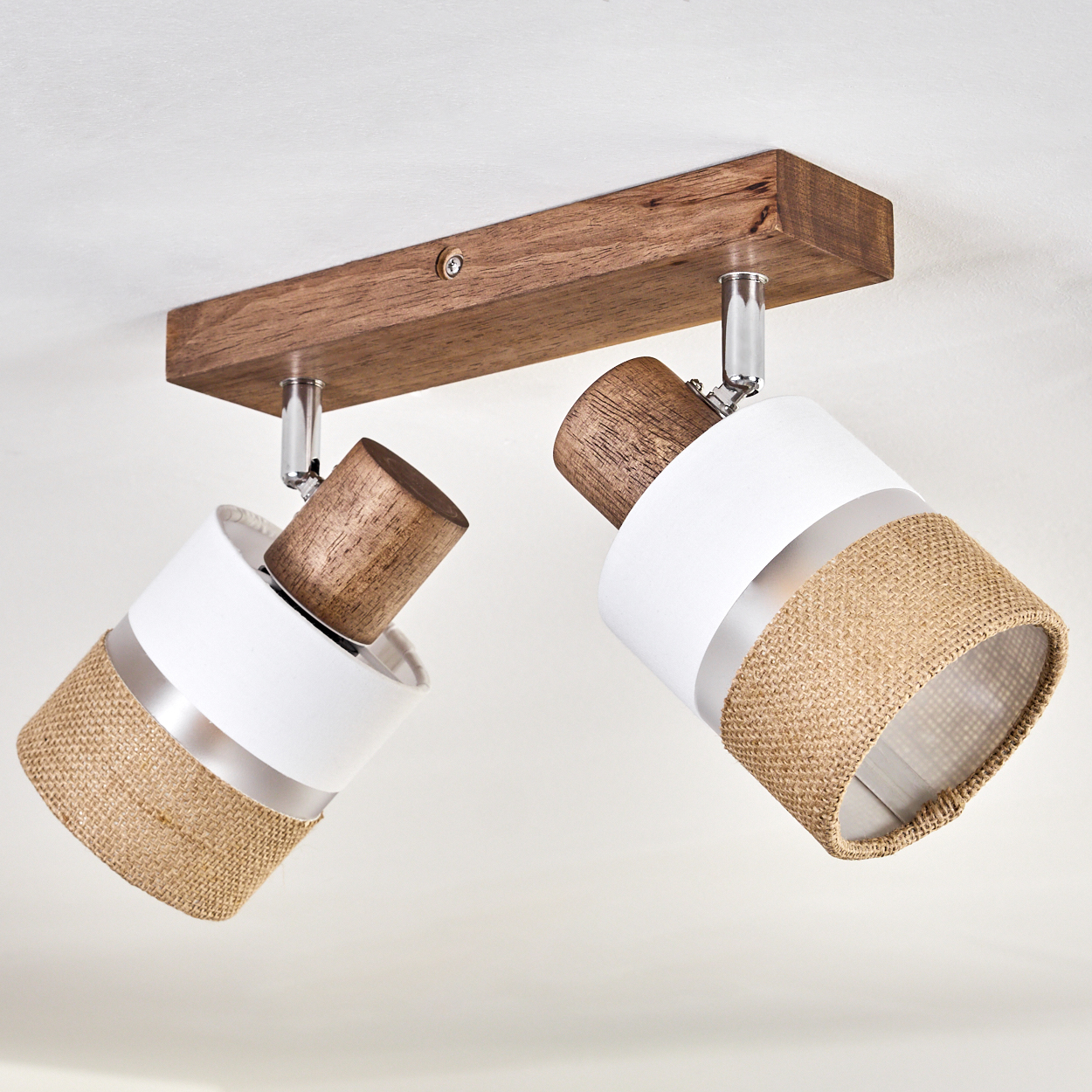 Zwei weiße und beige Lampen an einem Holzbalken. Die Lampen sind abgewinkelt und an der Decke befestigt.