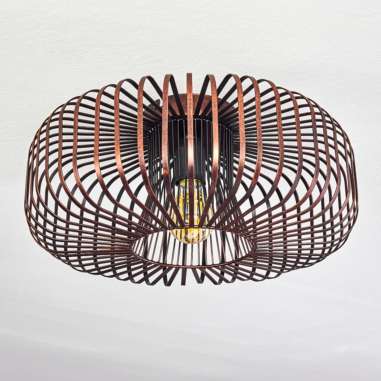 Käfigleuchte mit Glühbirne, Metallrahmen und brauner Oberfläche vor weißer Decke.