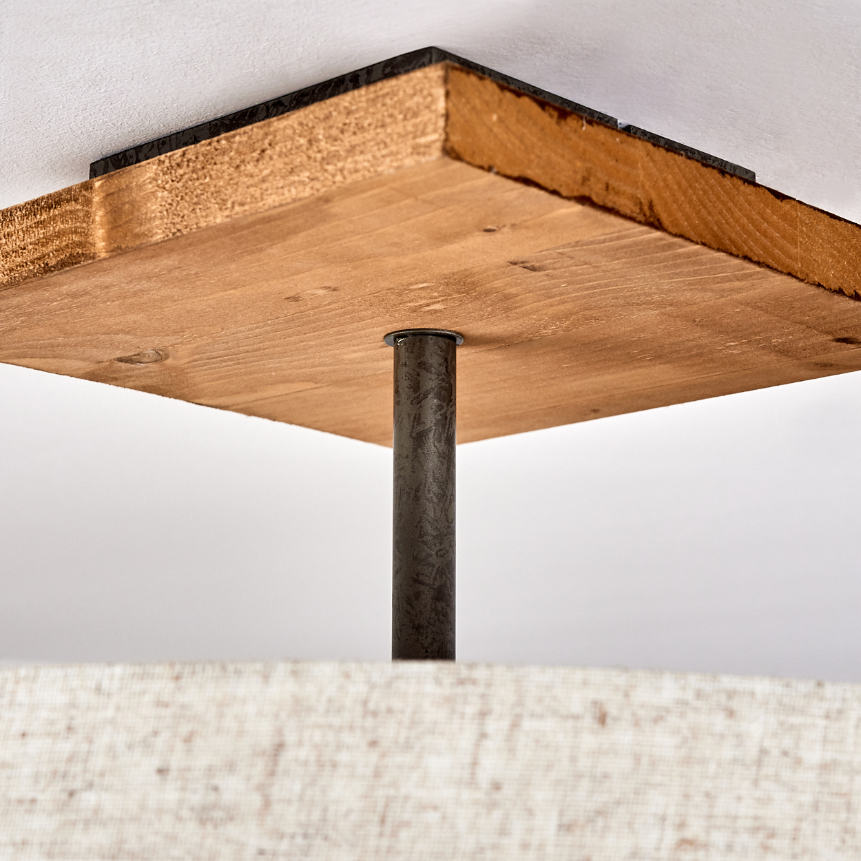 Eine quadratische Holzdecke mit Metallstange, die eine Lampenschirm aus beigem Stoff hält.