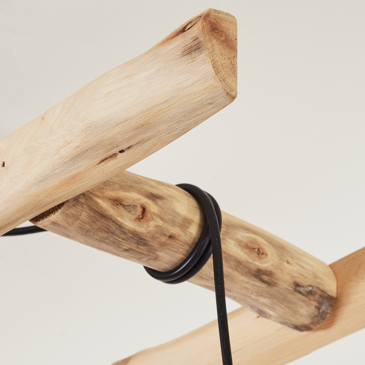 Nahaufnahme einer Holzleiter mit schwarzem Kabel, das um die Sprossen gewickelt ist, natürliches Licht.