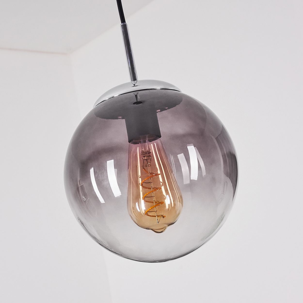 Nahaufnahme einer Pendelleuchte mit kugelförmigem, farbverlaufenden Glasschirm und sichtbarer Glühbirne.