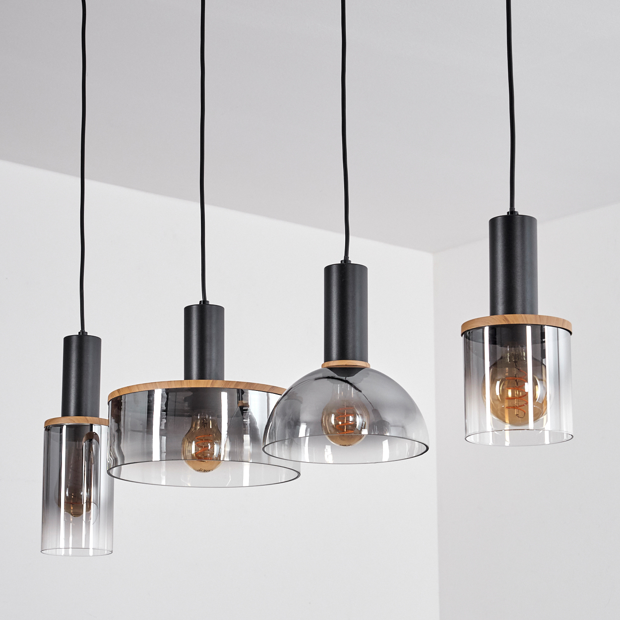 Vier Pendelleuchten mit transparenten Glasschirmen mit Holzakzenten.