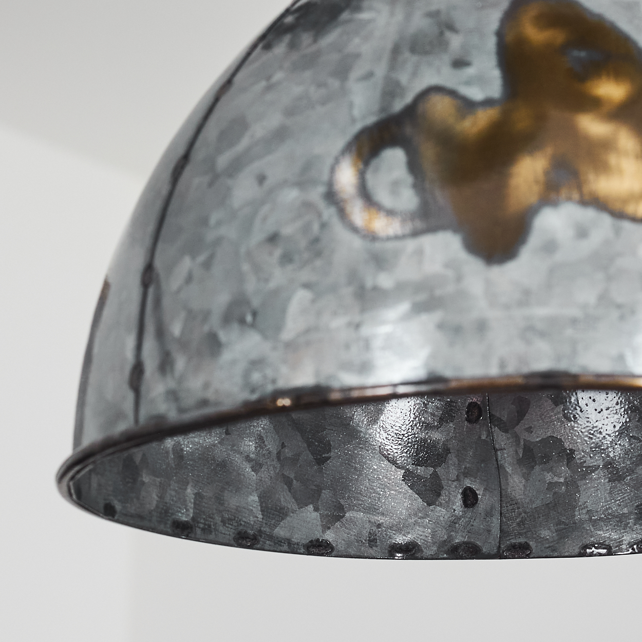 Nahaufnahme einer grauen Metallpendelleuchte, die ihre strukturierte Oberfläche und Nietkonstruktion zeigt.