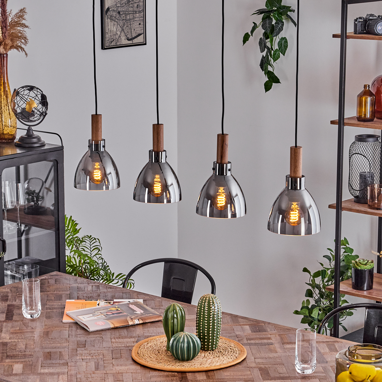 Esszimmer mit Pendelleuchten. Vier Pendelleuchten über einem Holztisch, mit Pflanzen und Dekoration.