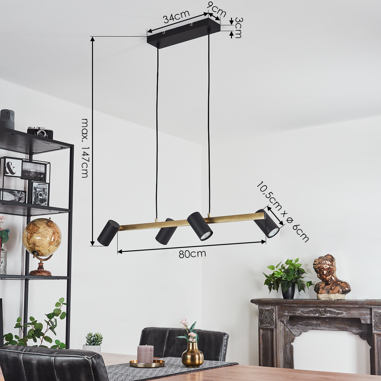 Eine Lampe mit drei schwarzen Strahlern hängt von der Decke. Es hat goldene Akzente und die Maße sind beschriftet.