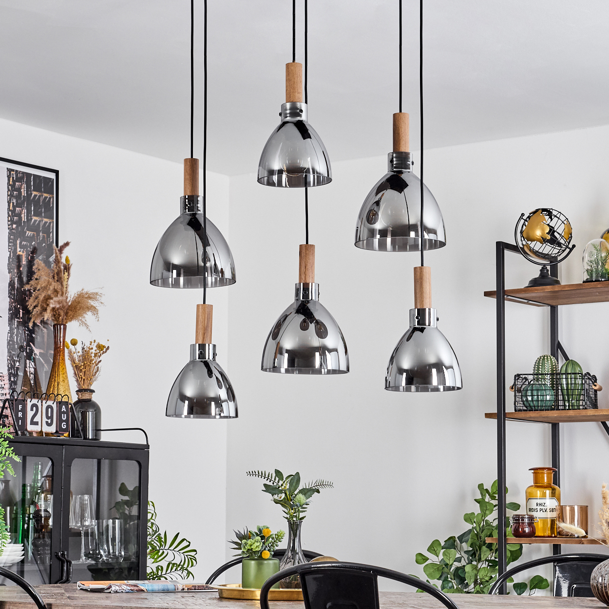 Ein Esszimmer mit Hängelampen. Das Setting umfasst einen Tisch, Dekoration und ein Regal mit verschiedenen Gegenständen.
