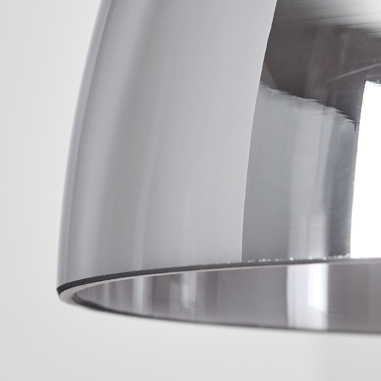Nahaufnahme eines Chrom-Lampenschirms mit grauem Finish, der Licht reflektiert, mit weißem Hintergrund.