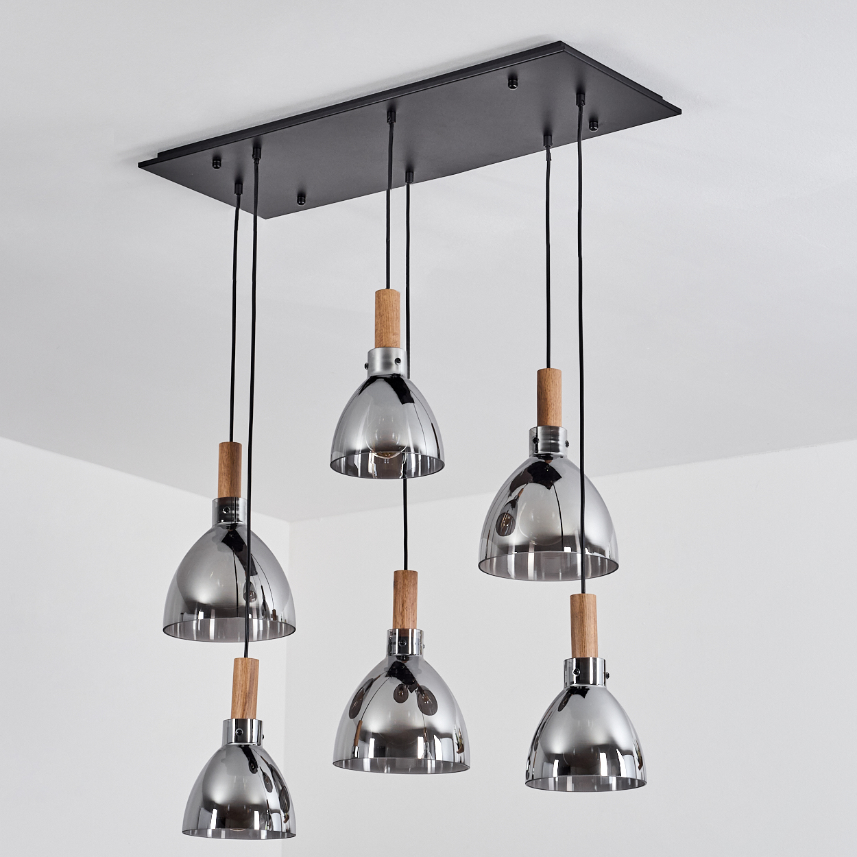 Sechs Pendelleuchten. Die Lampen sind silberfarben, mit Holzakzenten, hängen von der Decke. Weißer Hintergrund.