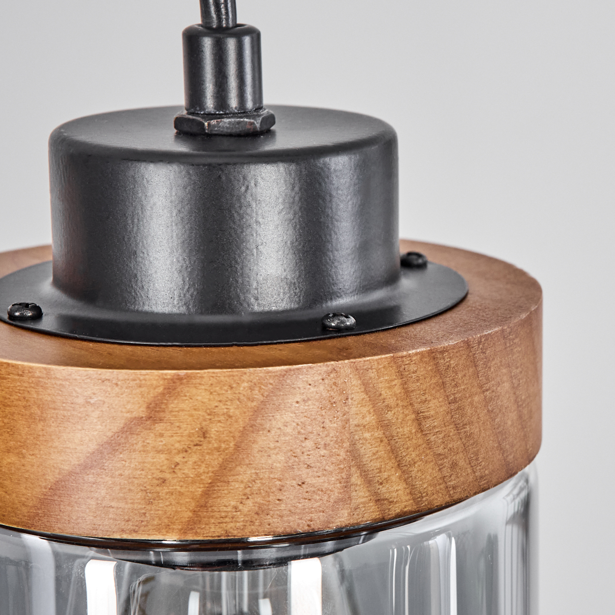 Nahaufnahme einer Lampe. Die Oberseite ist aus Holz mit einem schwarzen Ring. Eine schwarze Schraube ist sichtbar. Weißer Hintergrund.