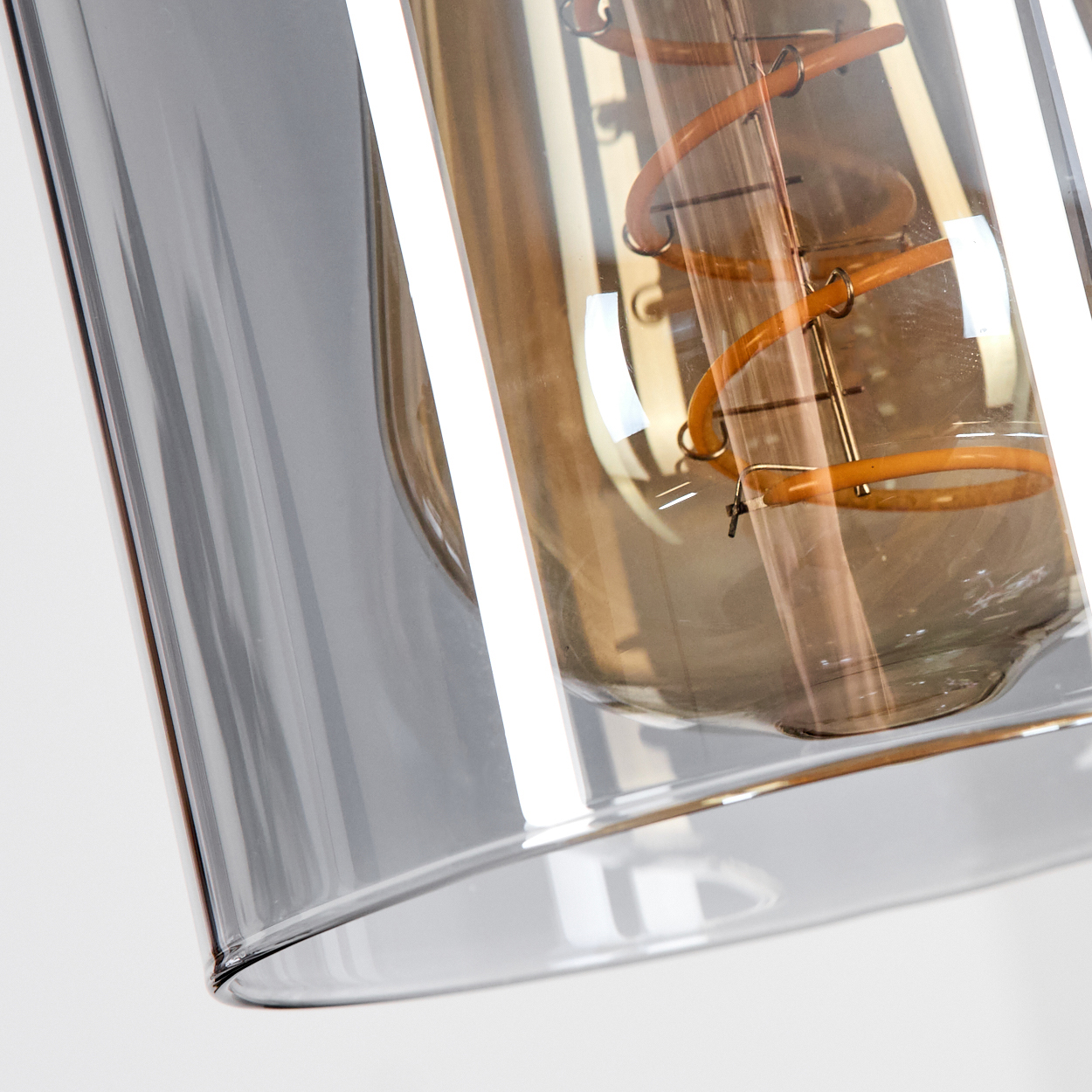 Nahaufnahme eines Glasschirms einer Pendelleuchte mit einer Glühbirne. Die Glühbirne hat einen Spiralfaden.