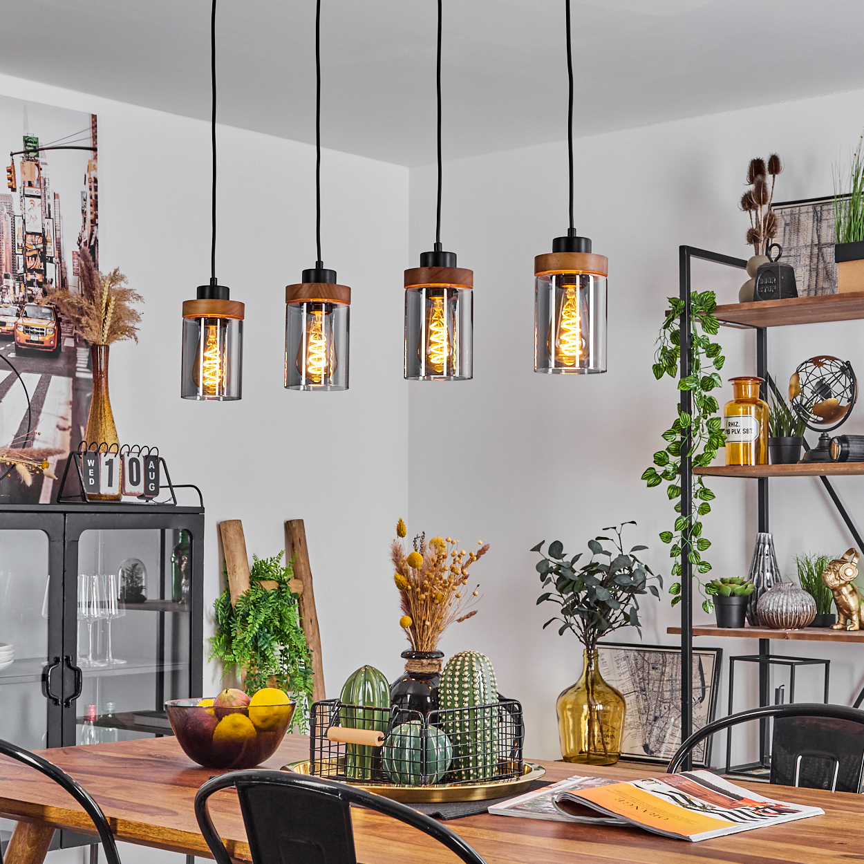 Esszimmer mit vier Pendelleuchten mit Glasschirmen und Holzakzenten. Die Leuchten befinden sich über einem Tisch.