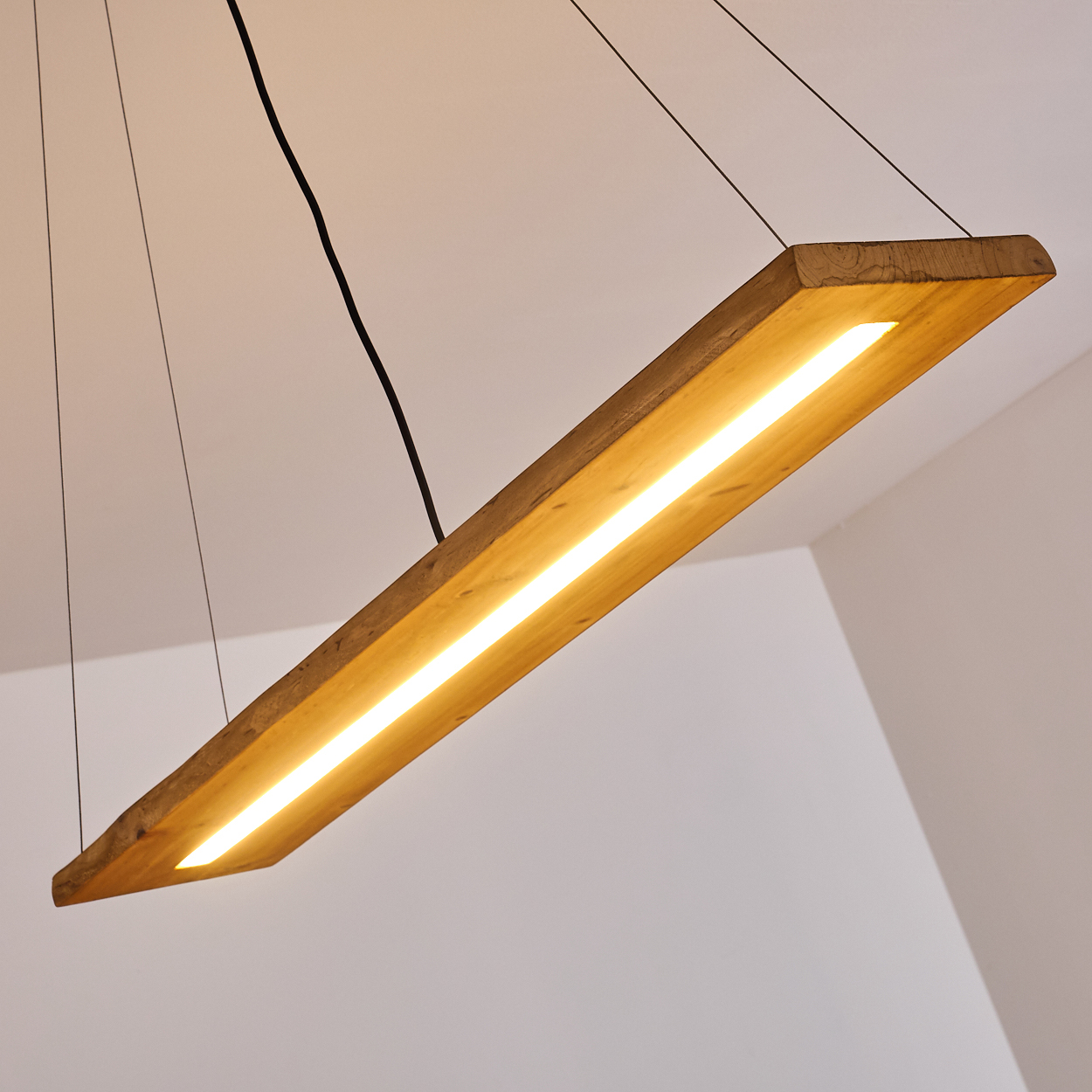 Eine rechteckige Holzbalken-Deckenleuchte mit einem Lichtstreifen, hängt von der Decke.