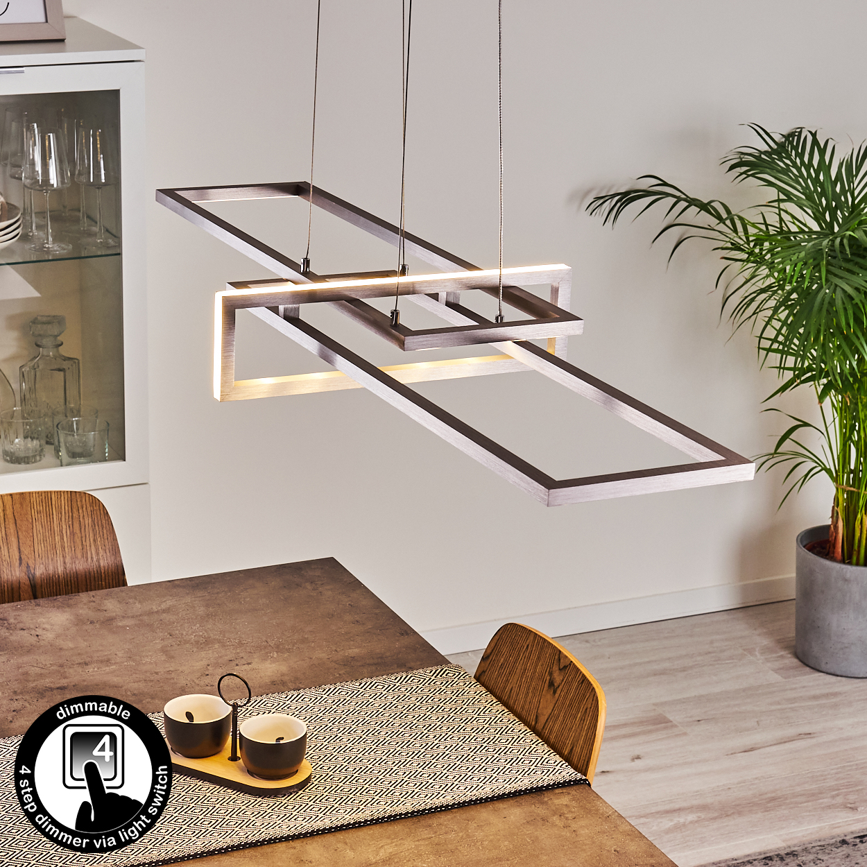 Moderne Pendelleuchte mit miteinander verbundenen Rahmen über einem Tisch. Die Einrichtung umfasst Dekoration und einen Dimmschalter.