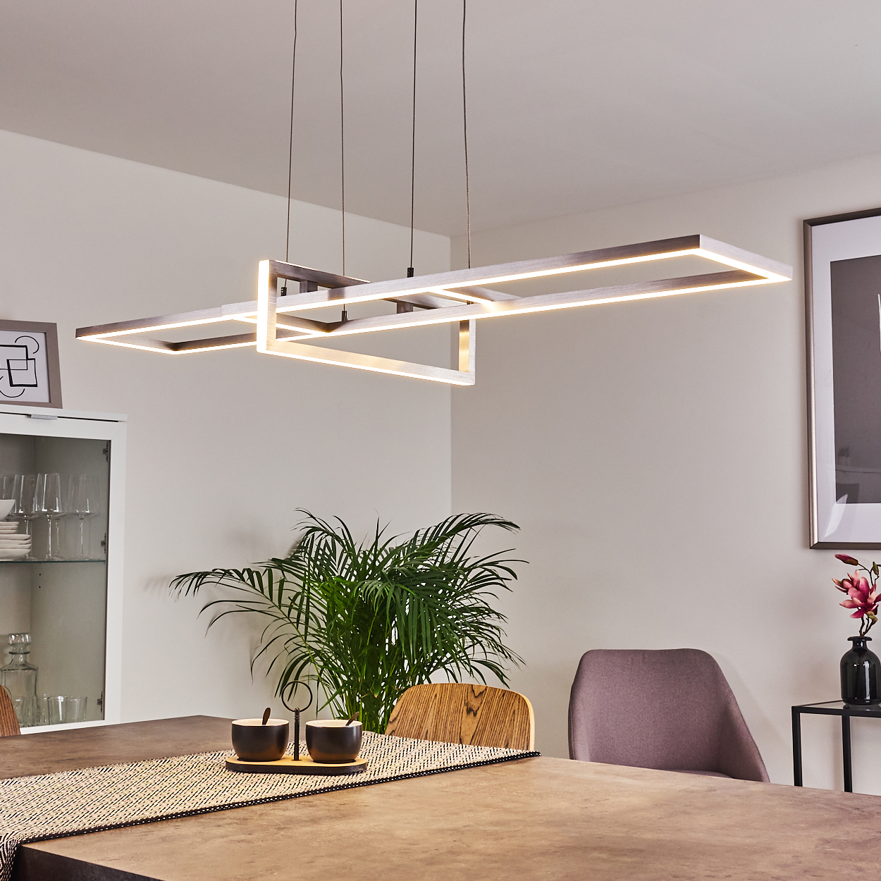 Esszimmer mit Hängeleuchte. Das Licht hat ein quadratisches Design und strahlt warmes Licht aus.
