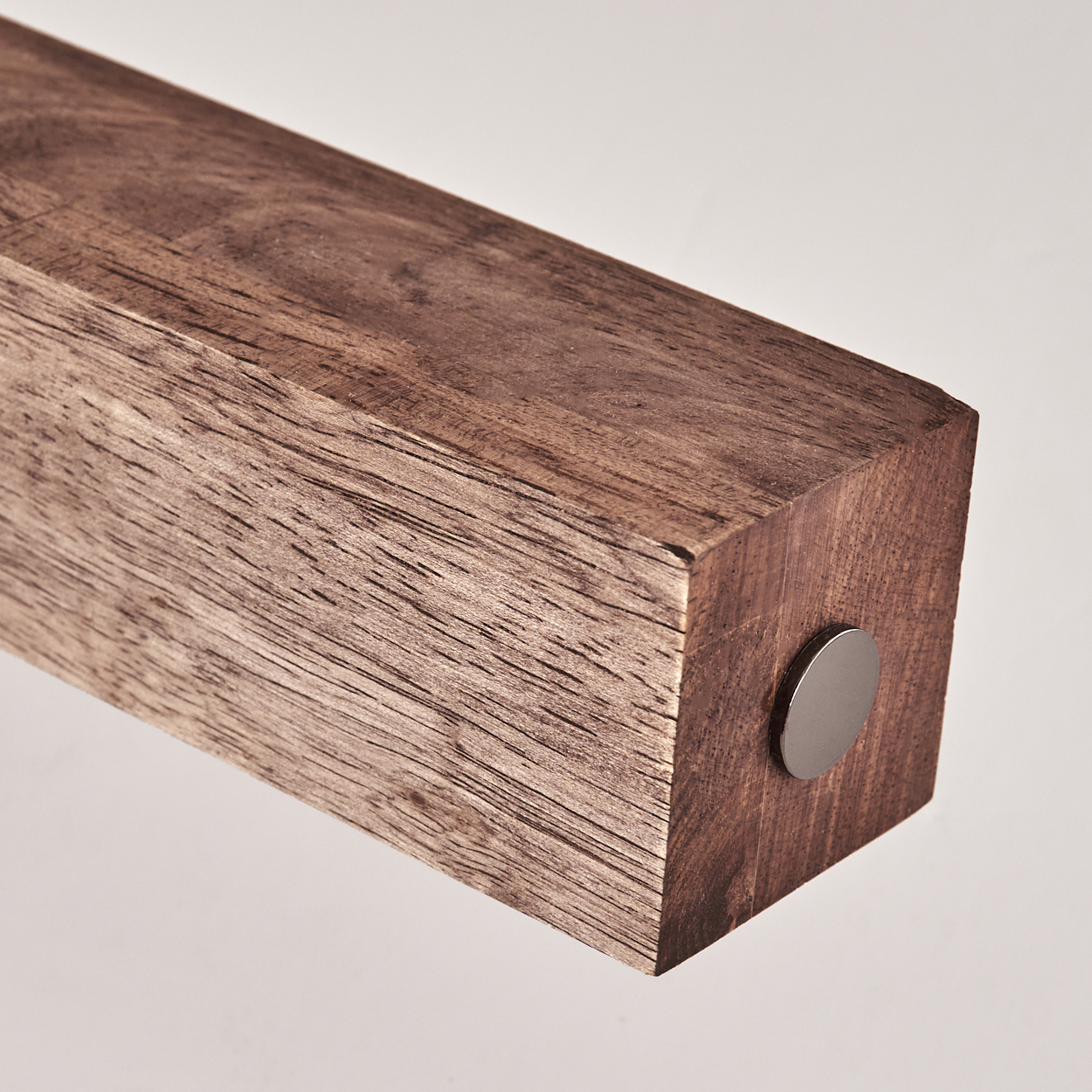 Nahaufnahme des Endes eines Holzbalkens. Es ist ein Rechteck aus Holz. Eine Metalltaste ist eingesetzt.
