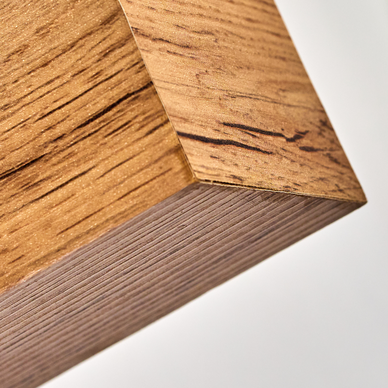 Nahaufnahme einer Holzplatte mit sichtbarer Maserung und dunkler brauner Kante. Weißer Hintergrund.